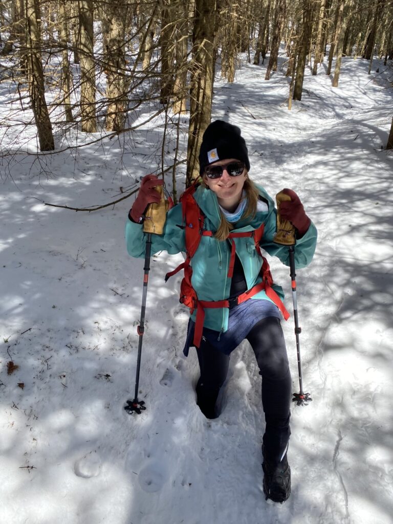 female winter hiker demonstrates getting stuck in a posthole