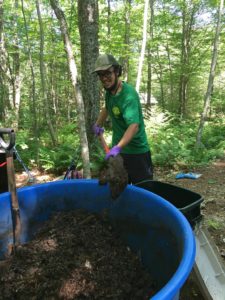 Caretaker stirring composting outhouse batch