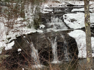 Waterfalls cascade over rocky winter terrain.