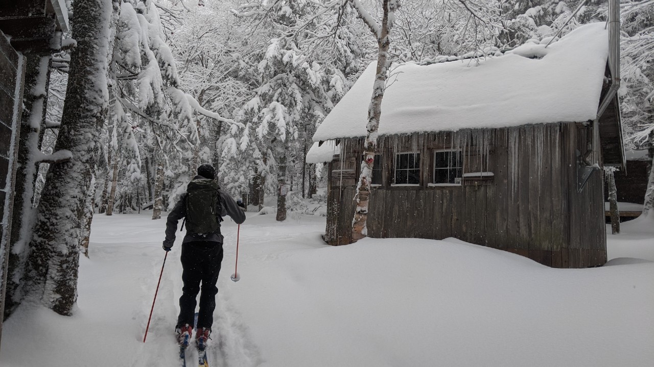 Skier moves through snow toward shelter for winter camping