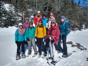 Colorfully dressed hikers pose in snowshoes..