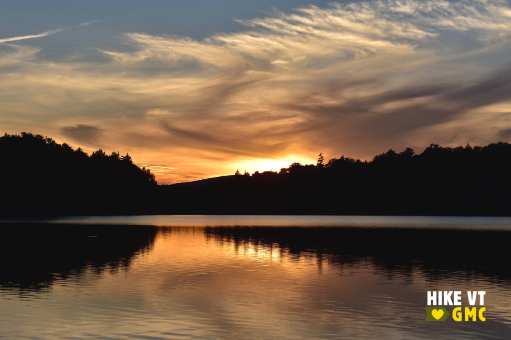Sun sets over a glassy Stratton Pond. Try this overnight hike.