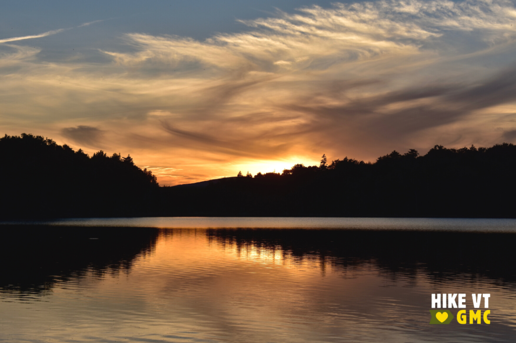 Sun sets over a glassy Stratton Pond.