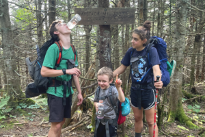 Charlie, Joe, and Ruth atMatt, Ruth, Joe, and Charlie Krebs with donuts on Long Trail. a trail sign for Haystack Mt.