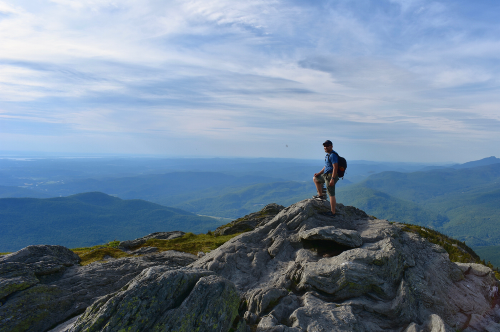 hiker stands triumphantly on a rocky summit