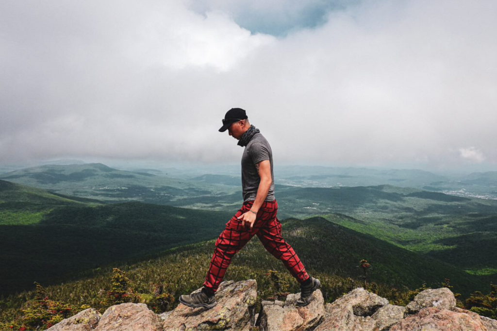 Hiker walks across a rock surface in forefront of photo.