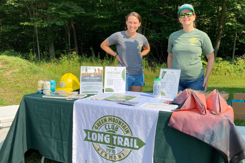 GMC staff Chloe Miller and Alicia Dicocco table at Barnes Camp Visitor Center on Long Trail Day 2022..