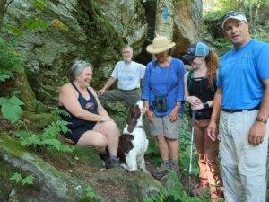 four hikers and one dog pose for a picture in the woods