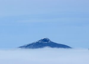 the rocky ledge of camel's hump peeks out over a thick layer of clouds