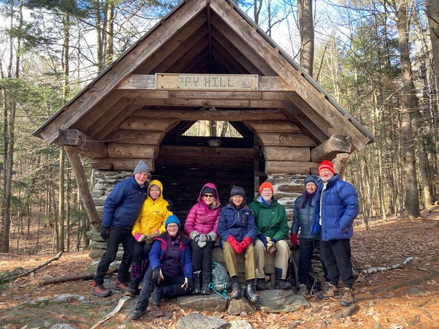 hikers gather in front of a wooden shelter