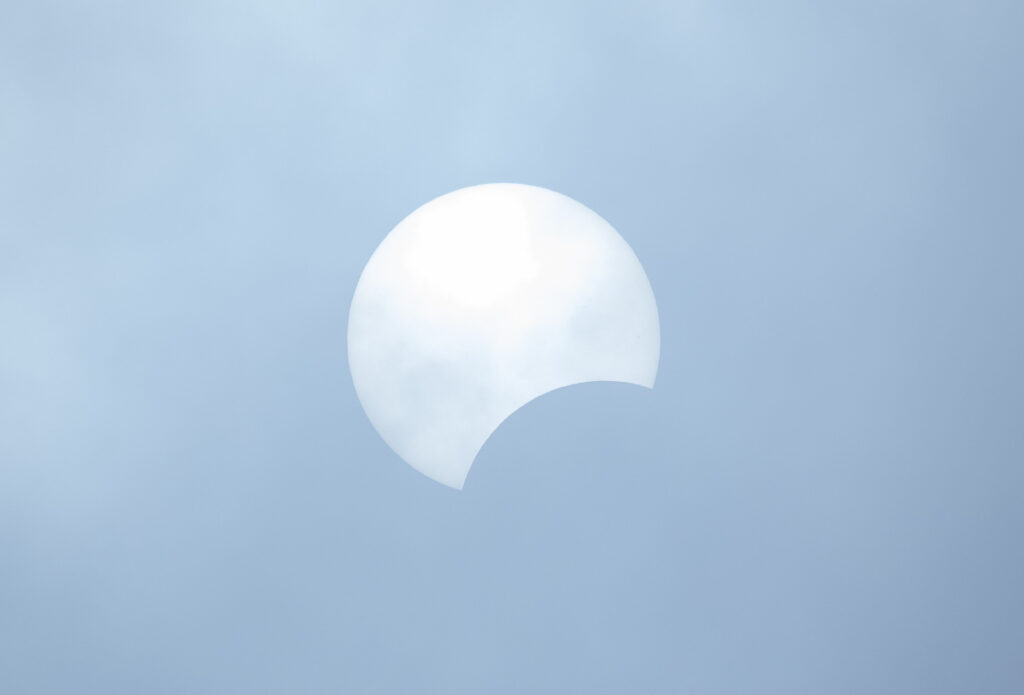 The outline of the moon partial obscures the midday sun during a partial solar eclipse on October 14, 2023.