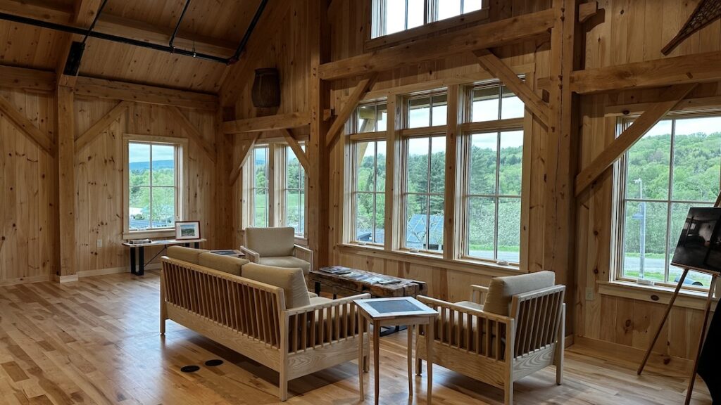 a bright, wooden timber frame room with several windows and light wooden furniture