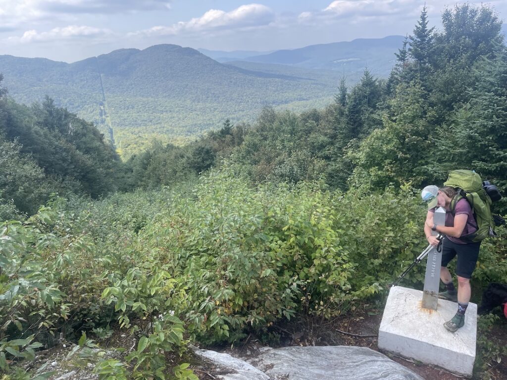 Samara Anderson hugs the Journey's End monument after completing her Long Trail End to End.